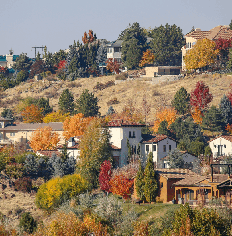 Houses on a hillside surrounded by colorful autumn trees.